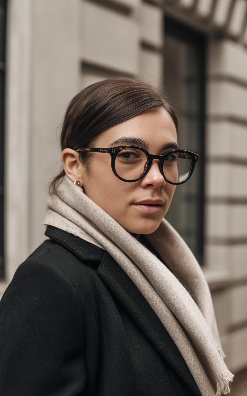 Black horn rim glasses styled with a wool coat and scarf